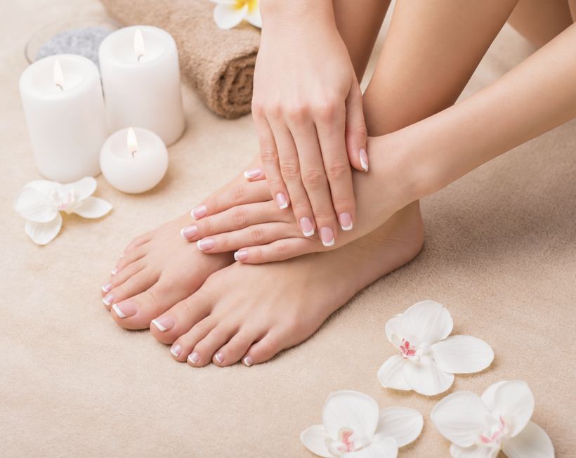 Manos y pies en un spa con velas y flores